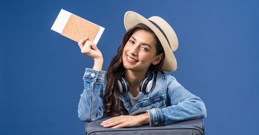 Happy young Asian woman holding passport with boarding pass and