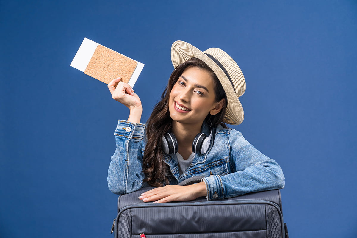 Happy young Asian woman holding passport with boarding pass and