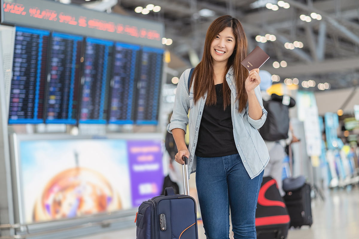 Portrait of Asian traveler with luggage with passport standing o
