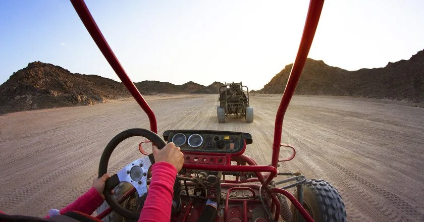 Cropped Image Of Tourists Riding Beach Buggies On Dessert Agains