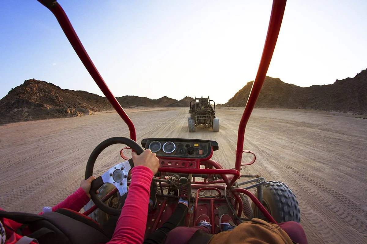Cropped Image Of Tourists Riding Beach Buggies On Dessert Agains