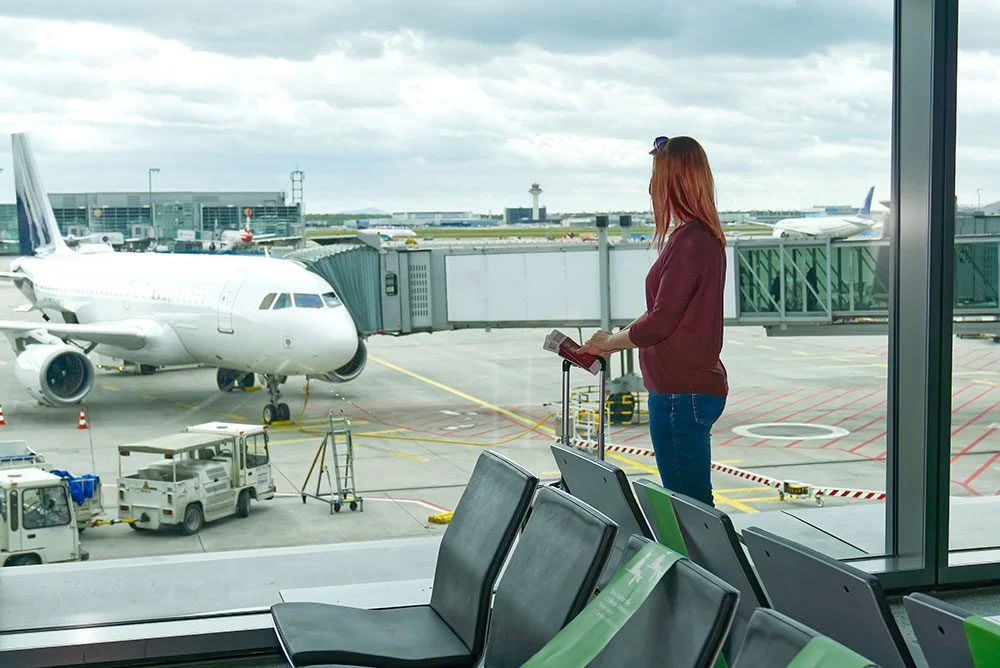 woman-at-the-airport-window-and-flight-departure-2023-04-20-20-33-39-utc