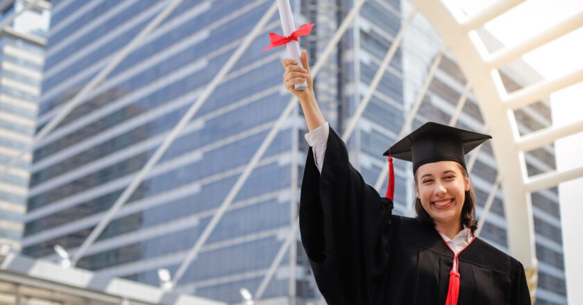 Estudante sorrindo e segurando o diploma com a mão direita
