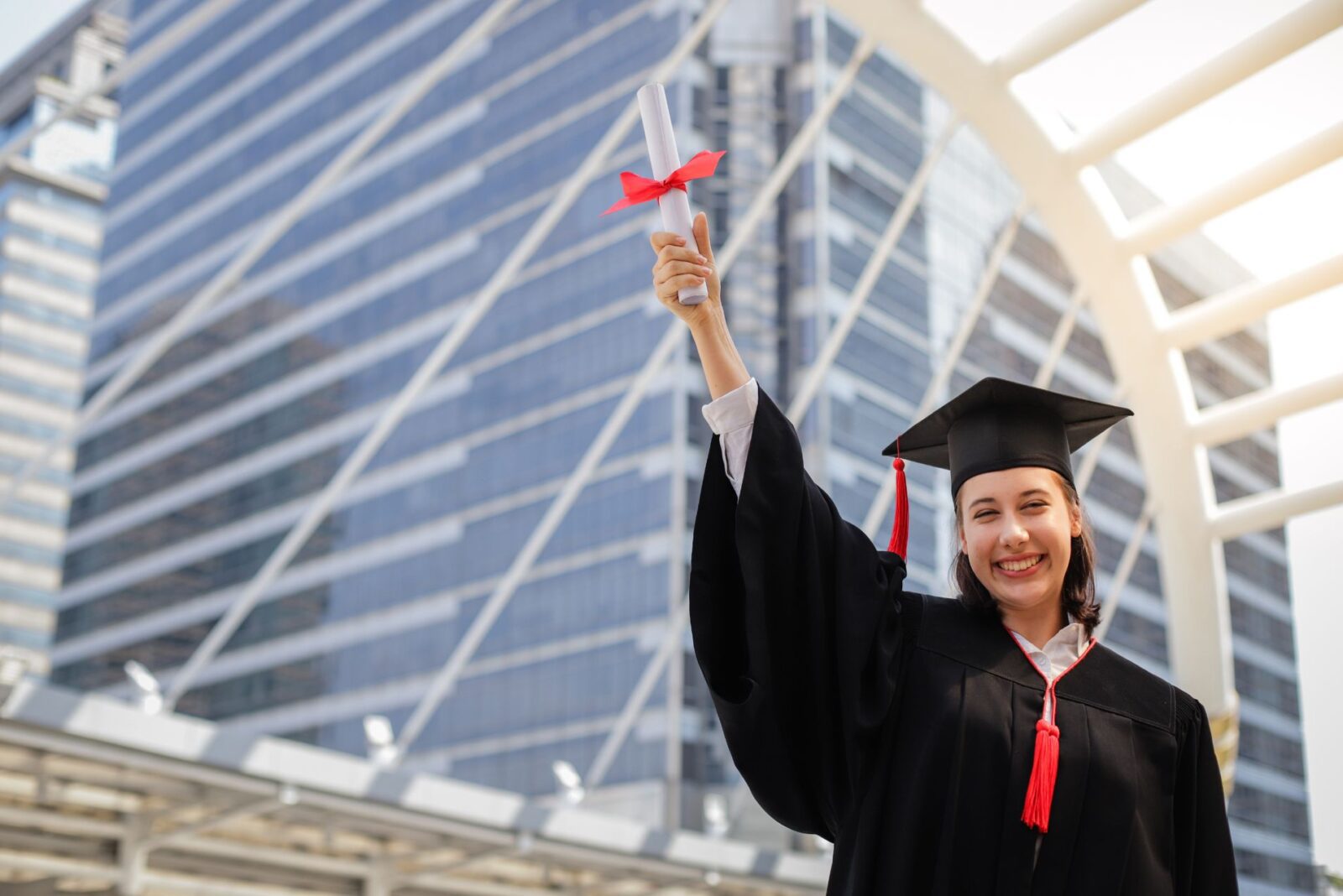 Estudante sorrindo e segurando o diploma com a mão direita